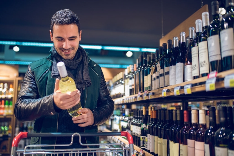 Imagen de un chico comprando vino en el supermercado