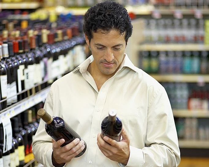 hombre comprando vino en supermercado