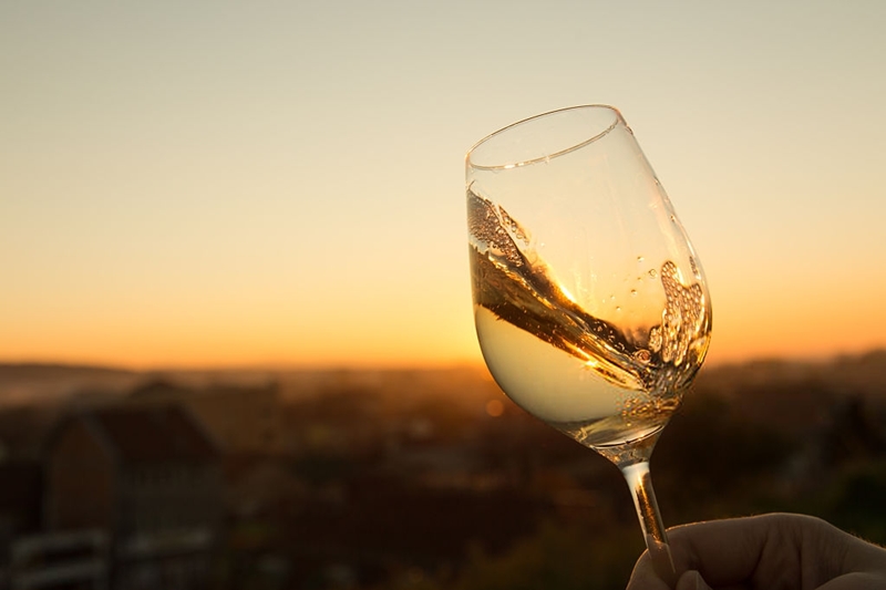 Imagén de una copa de vino blanco durante un atardecer