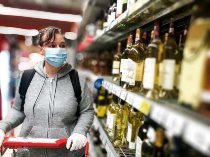 Imagen: Chica comprando vino en un supermercado en la era Covid