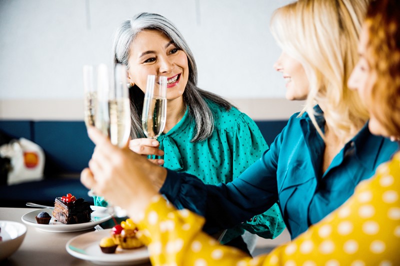 Mujeres tomando postre y vinos espumosos