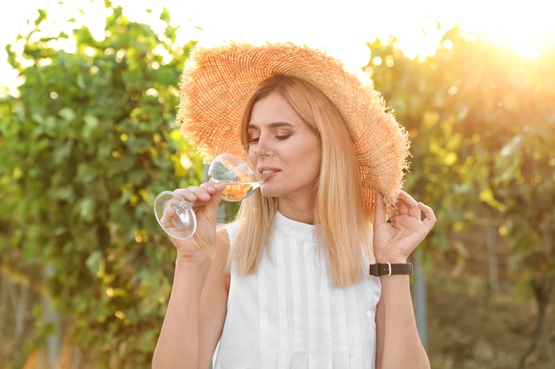 Mujer bebiendo vino en viñedo
