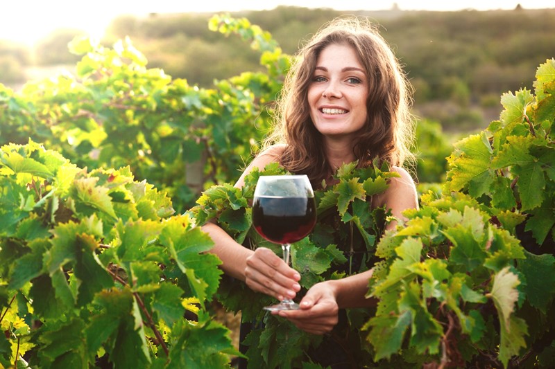 mujer entre viñas con una copa de vino tinto