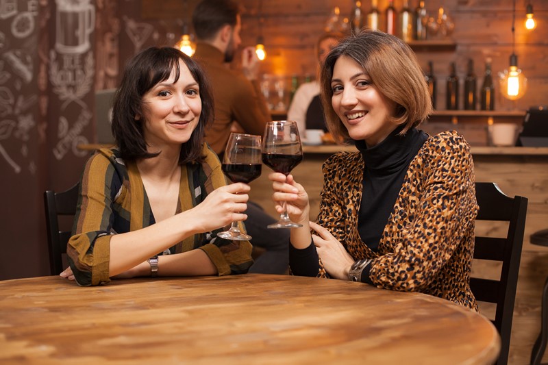 dos mujeres tomando vino en un bar