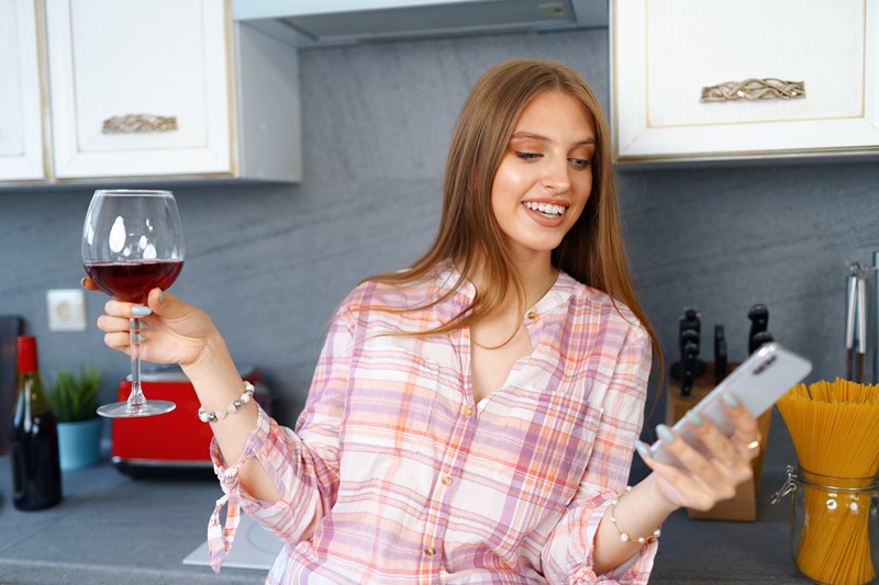 Mujer con un smartphone y una copa de vino