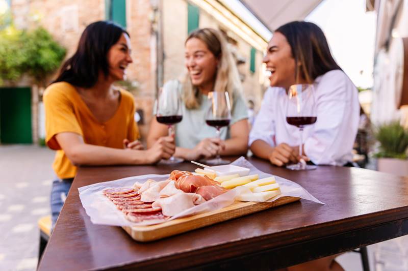 Tres amigas en un restaurante español tomando unos vinos y unas tapas